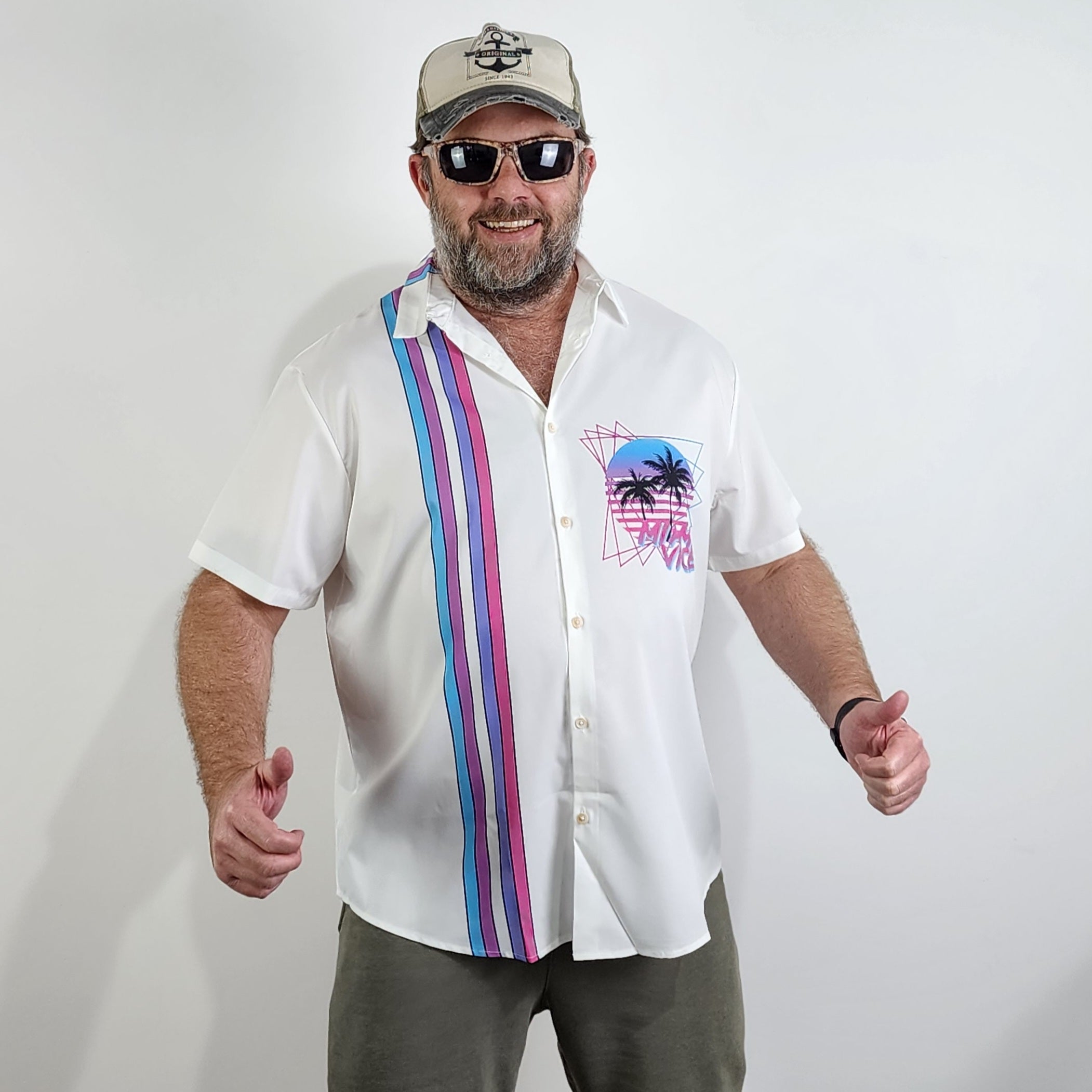 Man wearing a white Miami Vice Hawaiian shirt. The shirt has neon 80s design. 
