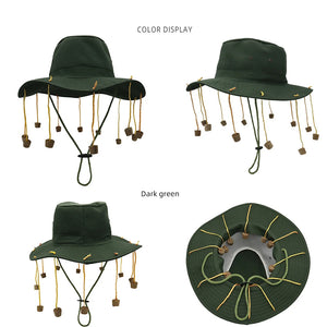 Dark green bucket cap with cork end tassels hanging down from the brim on a white background. 