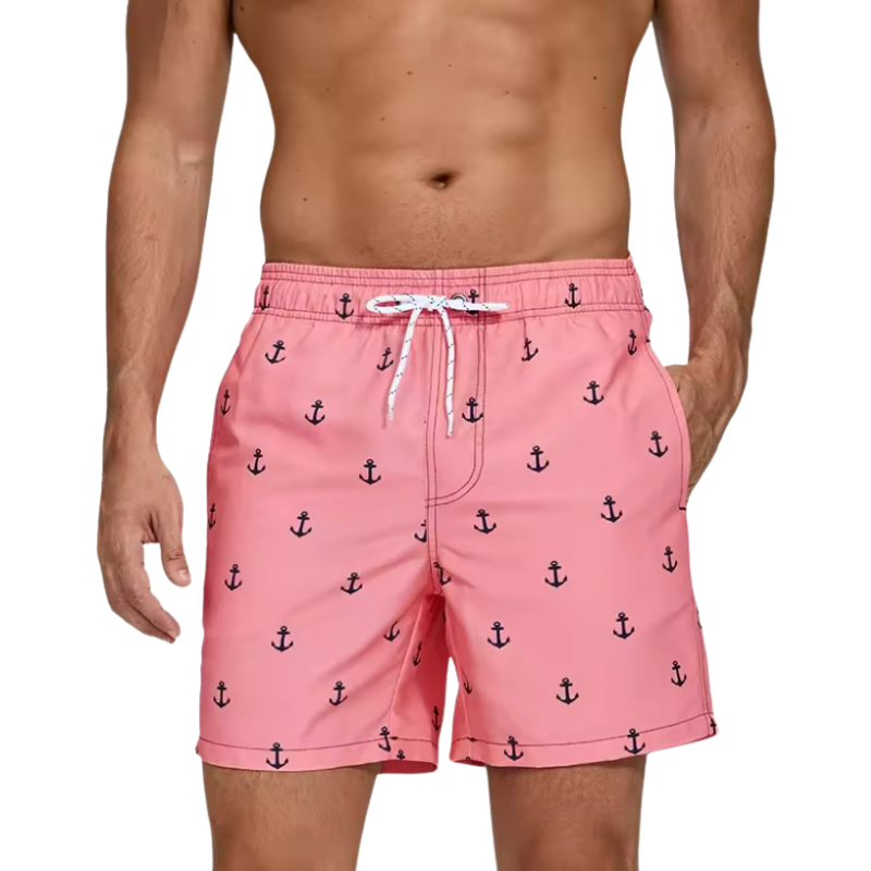 Pink swim shorts with anchor pattern worn by a person on a white background.