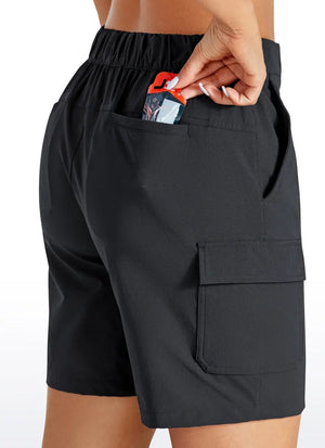 A lady wearing a black pair of quick drying hiking shorts while putting a card in the back pocket. The shorts have large cargo pockets on the side.