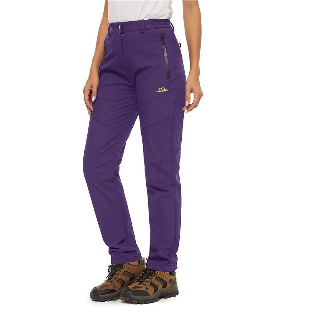 Female model wearing the Women's Waterproof Fleece Pants in colour purple. She is also wearing a white t-shirt and brown hiking boots.