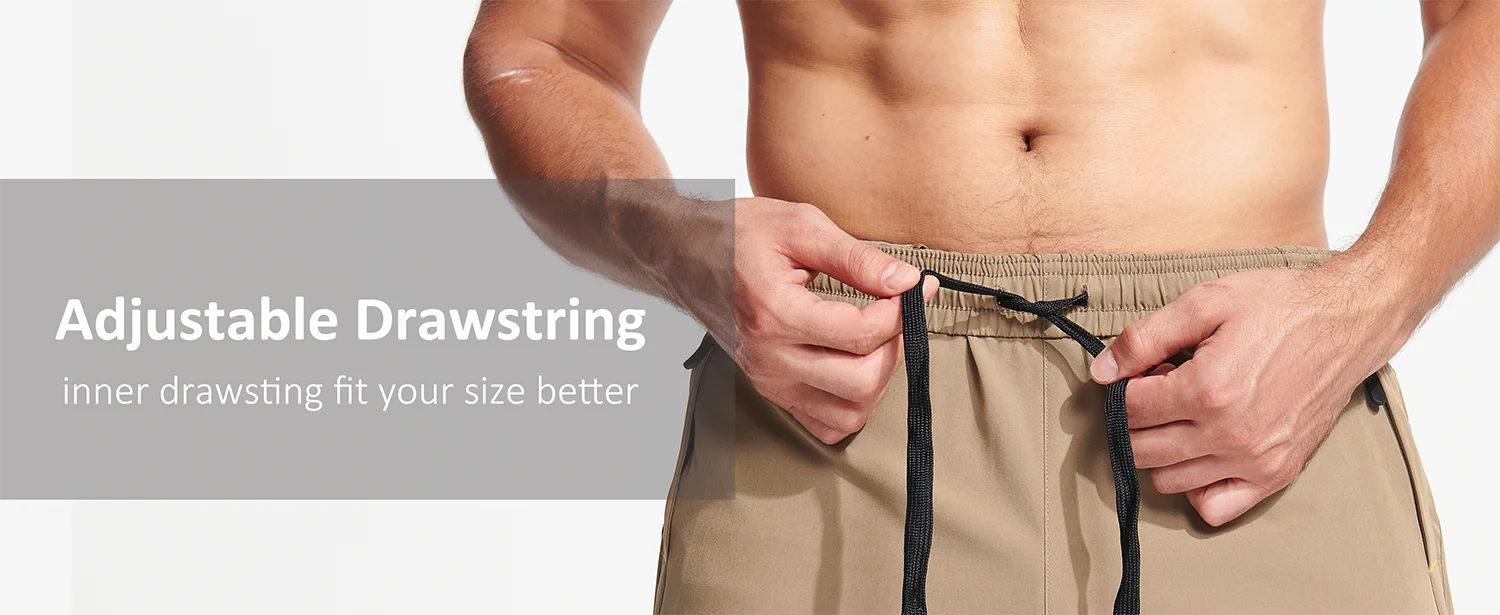 Person adjusting an adjustable drawstring on beige shorts with a grey background.