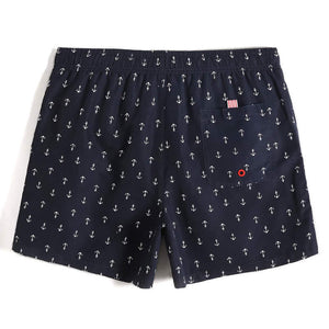 Men's navy blue shorts with white anchors and pocket on the back. Red eyelet on back pocket.