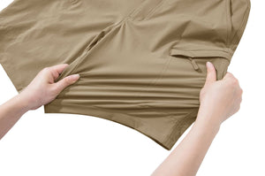 A person pulling on shorts to demonstrate how the fabric stretches. The shorts are khaki and have zip pockets.