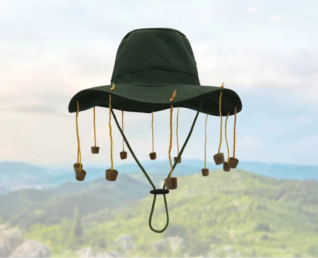 A green hat designed to keep flies off your face on bushland background. 