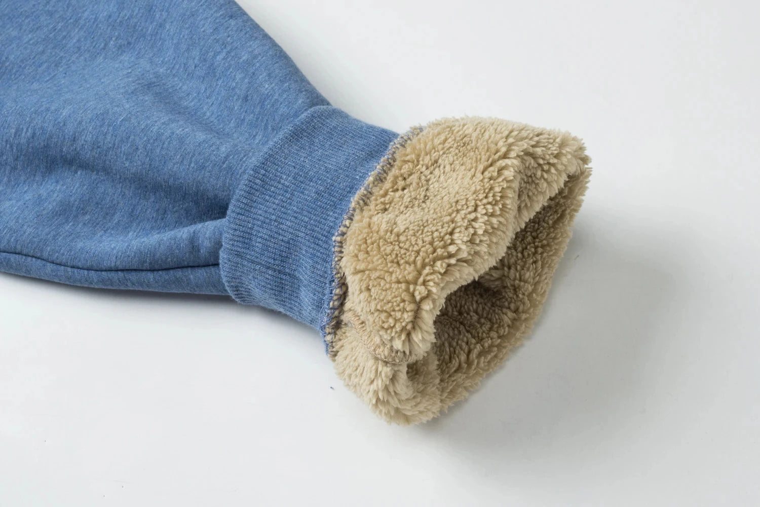 The sleeve of a jumper rolled back showing the thick sherpa fleece lining.