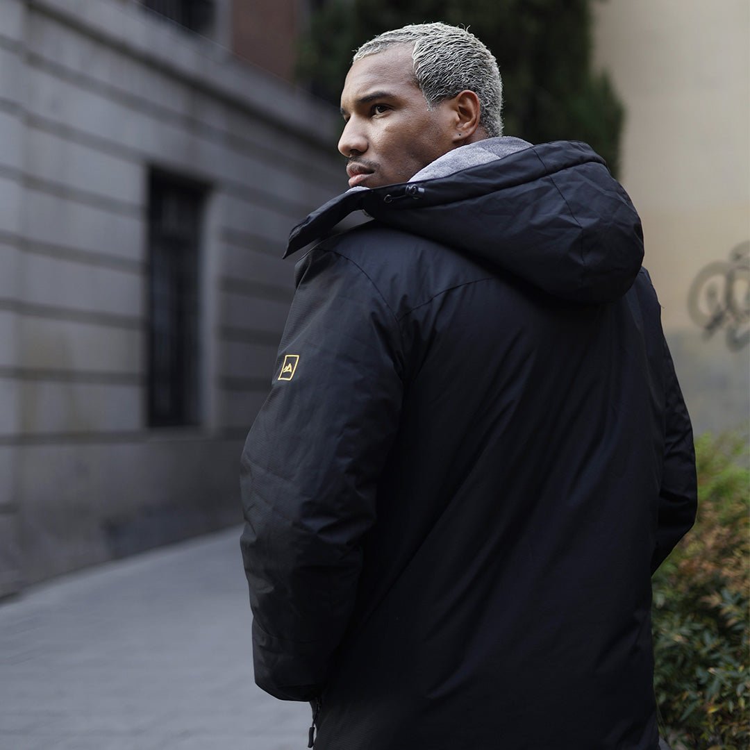 Man in urban environment wearing a thick black jacket.