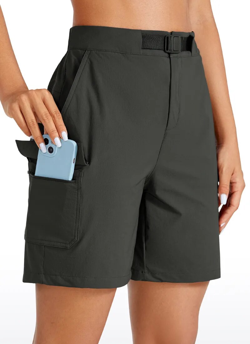 Female fitness model wearing a pair of mountain green hiking shorts while putting her mobile phone into the convenient cargo pocket.  The shorts also come with a belt.