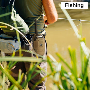 Man fishing on the riverbank with a walkie talkie attached to his belt.