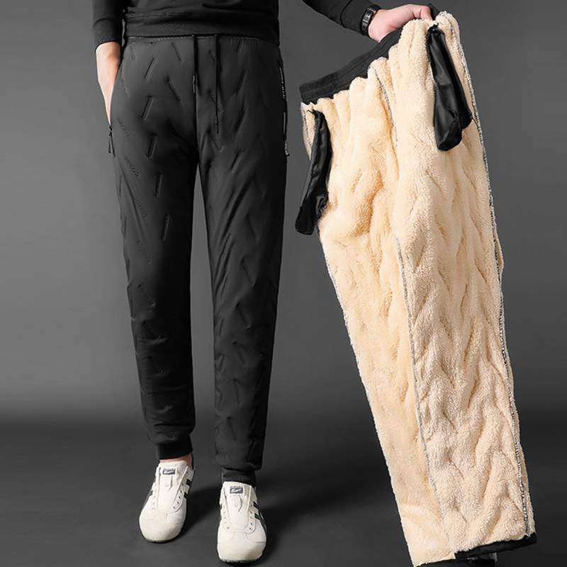 Male model wearing a pair of thick fleece lined pants while holing a pair inside out to show the fleece on the inside.