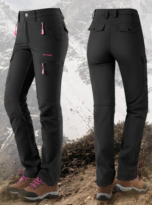 Women's waterproof fleece lined pants. Black with pink zipper tabs. Wite snowy mountain backdrop.