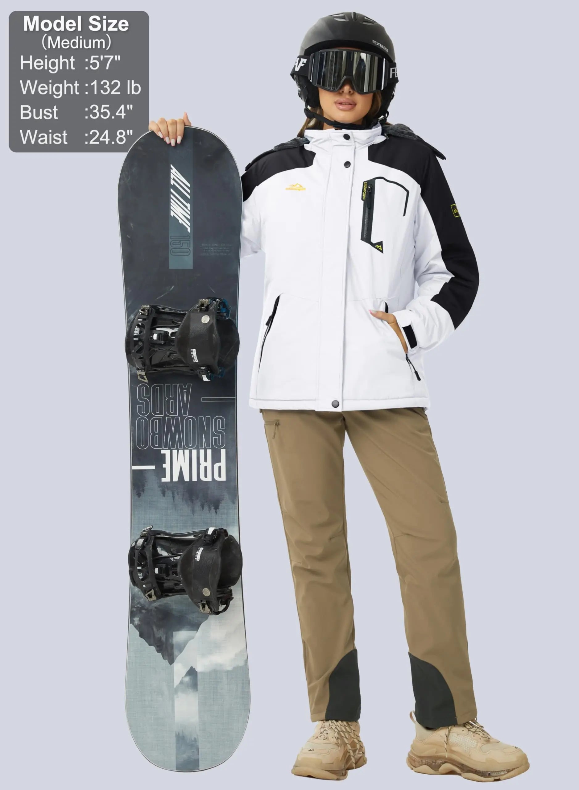 Female model wearing a black and white waterproof jacket while holing a snowboard. The model is also wearing a ski helmet, ski goggles and khaki pants. 