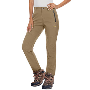 Female model wearing a pair of khaki pants that are waterproof and have a fleece lining. She is also wearing a white top and brown hiking shoes. 