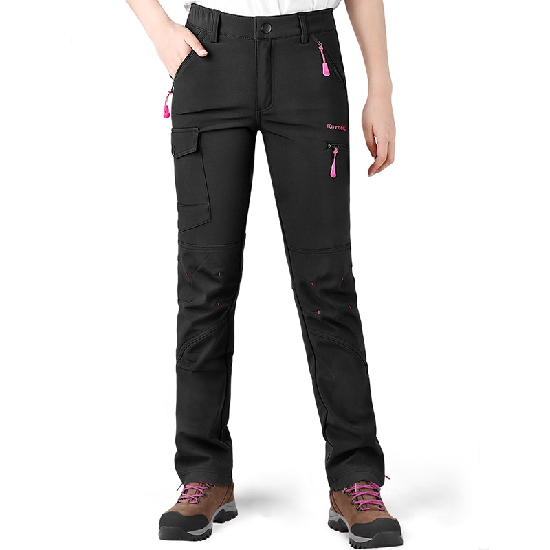 Women wearing a black pair of warm winter pants that have multiple zip pockets. The model is also wearing a white t-shirt and hiking shoes.