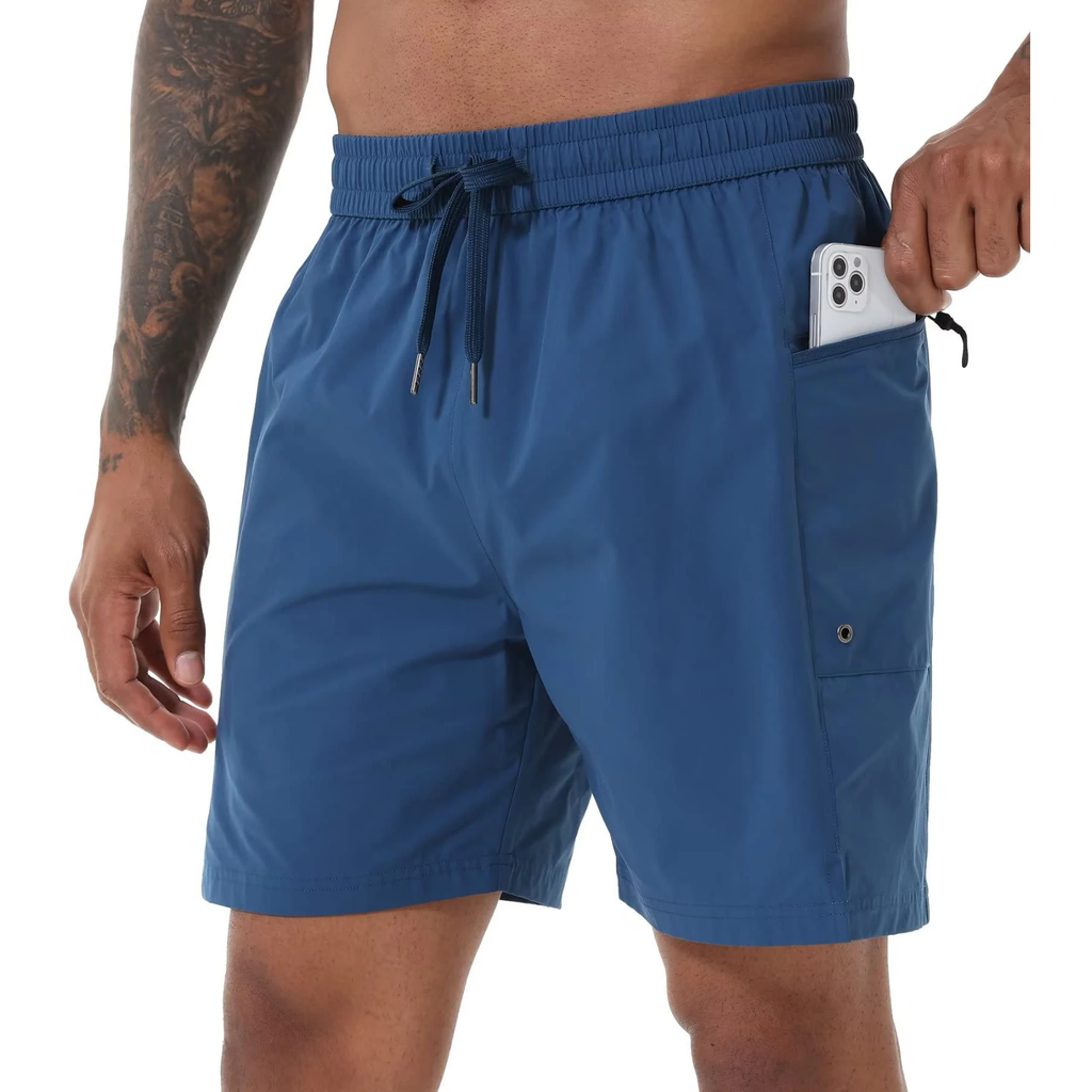 Male model wearing blue swim shorts while pulling a mobile phone out of his pocket. 