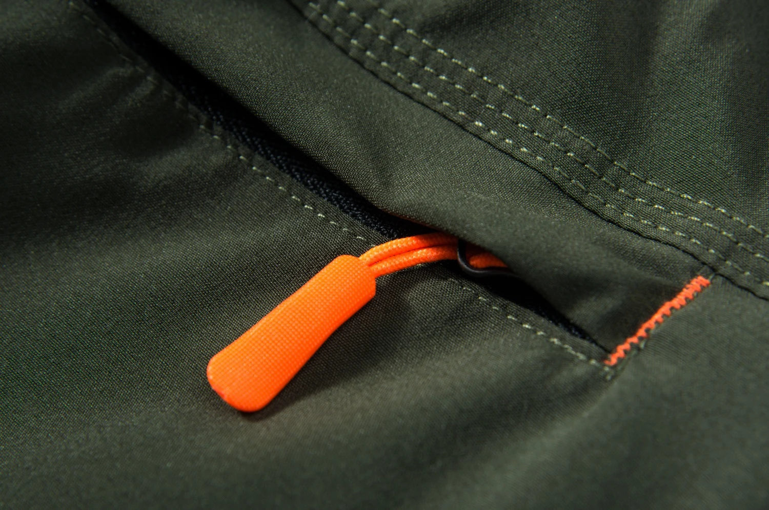 Close-up of a green pair of shorts with an orange zipper pull.