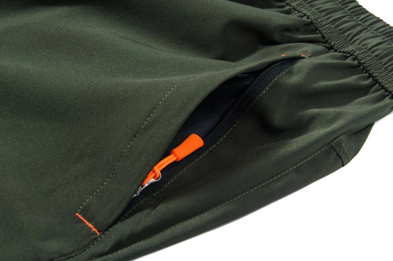 Close-up of green pants with an orange zipper on a white background