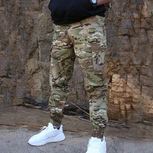 male model wearing Camoflaguge pants, black jumper and white shoes. 