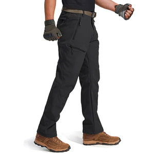 Man wearing a pair of warm black pants with multiple pockets. The pants have a fleece lining and they are made from waterproof fabric.