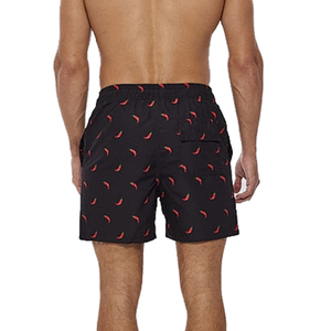 Man wearing a pair of shorts with a red chili pepper design.