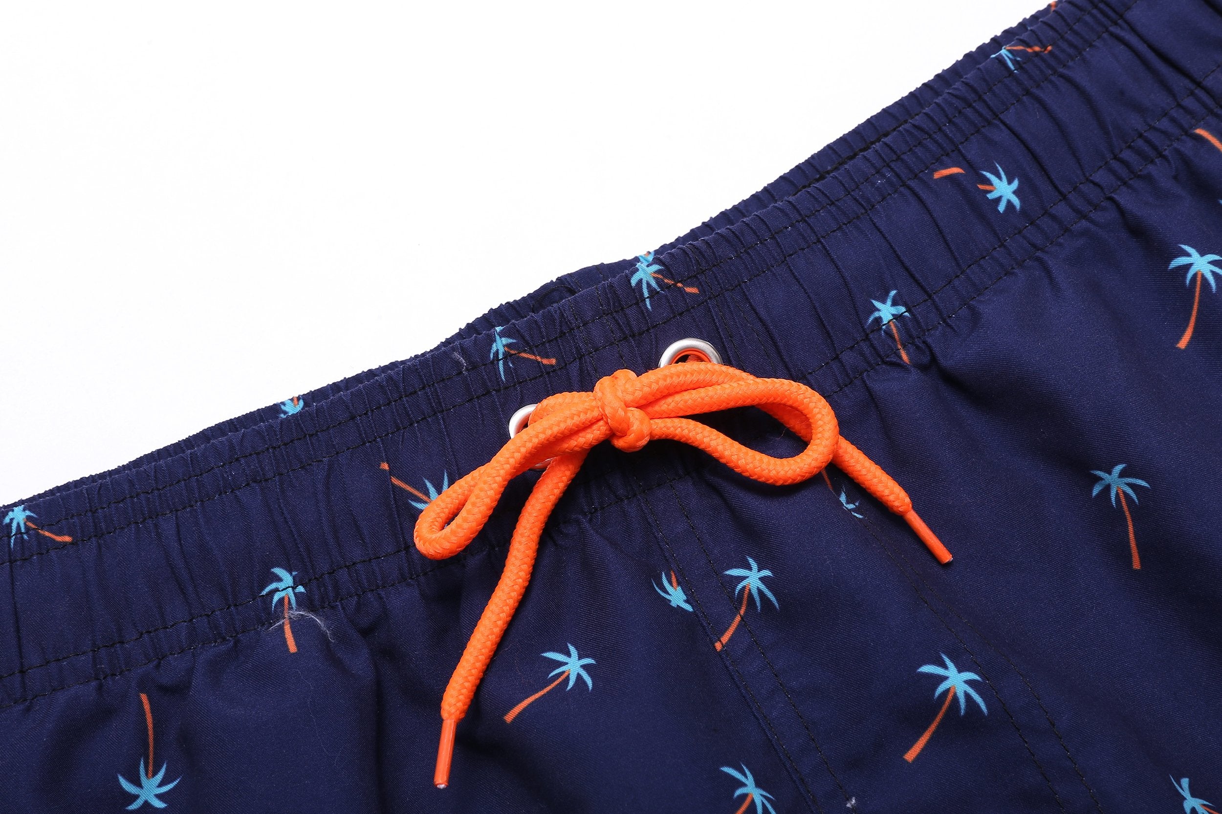 Orange drawstring on a pair of beach shorts with a palm tree design.