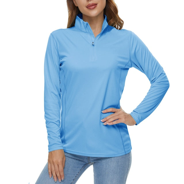 Female wearing a light blue long sleeve sun protection shirt. The shirt has a quarter zip up collar and has a sun protection rating of UPF 50+.
