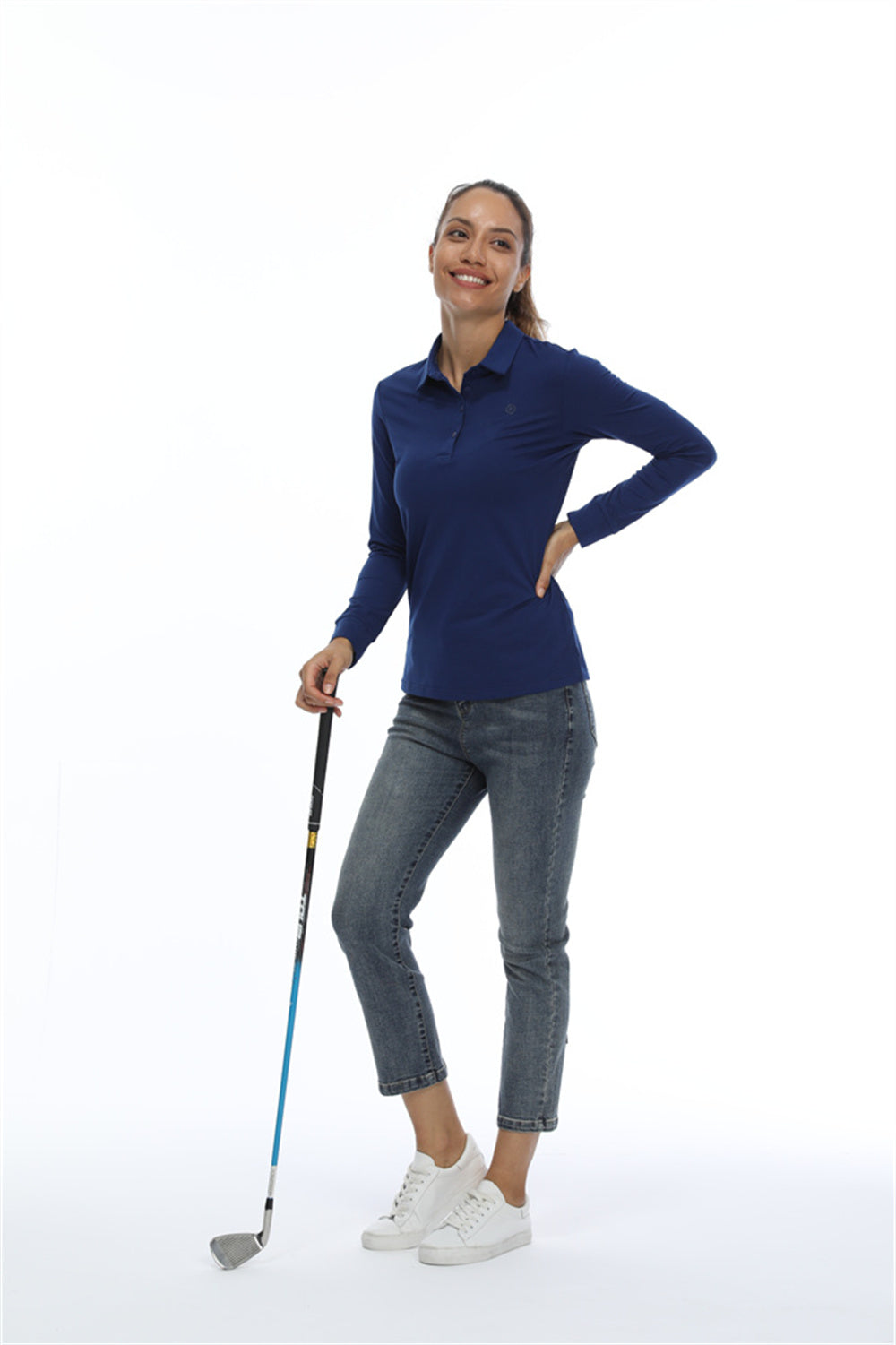 Female modelling a navy sun protection shirt while holing onto a golfclub. 