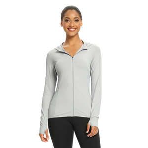 Female model wearing a light grey zip-up sun protection shirt with a UPF 50 + rating. The shirt has long sleeve, a hood and thumb holes in the sleeve cuff..